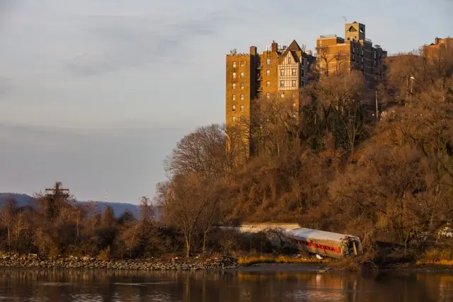 The wreckage of a Metro-North commuter train lies on its side after it derailed just north of the Spuyten Duyvil station